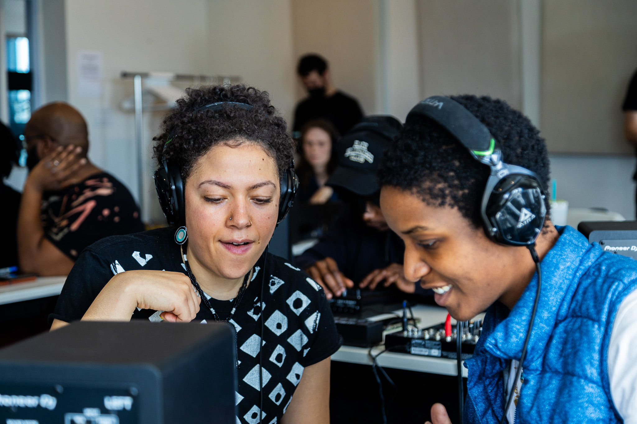 Two UMA students working together with headphones on.